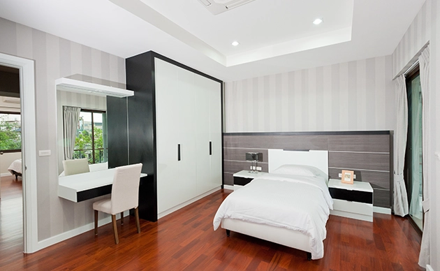 Remodeled bedroom with upholstered headboard, accent lighting, and layered bedding