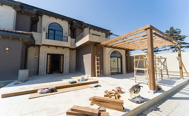 Construction worker framing a new room addition onto a stucco house